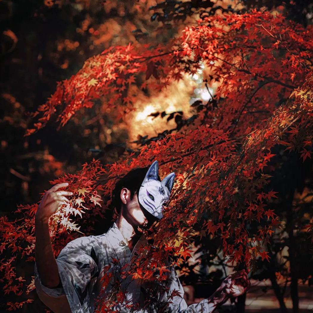 燃え盛るような紅葉と狐面のポートレート写真